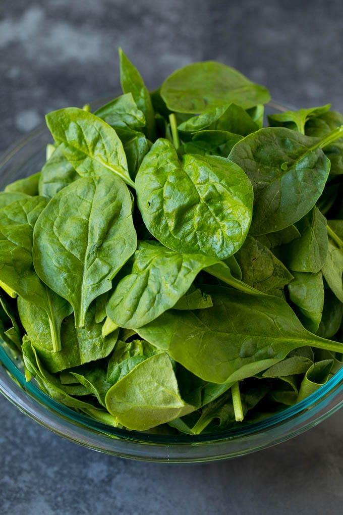 This creamed spinach is fresh sauteed spinach leaves in a flavorful cream sauce with parmesan cheese. Fresh spinach leaves in a bowl.