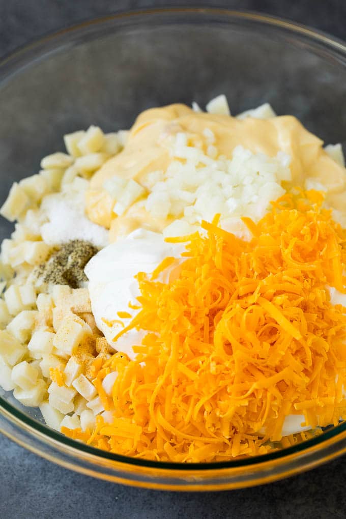 Funeral potatoes are creamy and cheesy potatoes that are topped with buttered cornflakes and baked to golden brown perfection. Potatoes, sour cream, grated cheese and seasonings in a bowl.