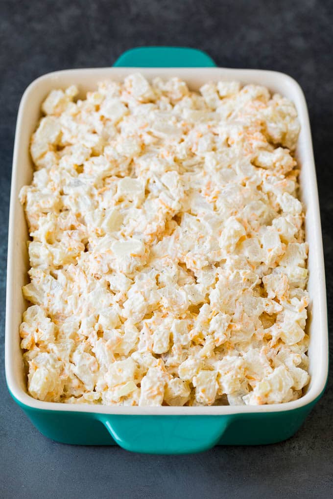 Funeral potatoes are creamy and cheesy potatoes that are topped with buttered cornflakes and baked to golden brown perfection. A mixture of potatoes with cheese and sour cream in a baking dish.