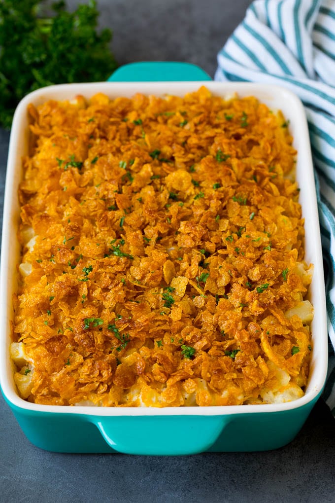 Funeral potatoes are creamy and cheesy potatoes that are topped with buttered cornflakes and baked to golden brown perfection. A dish of funeral potatoes topped with buttery cornflakes and parsley.