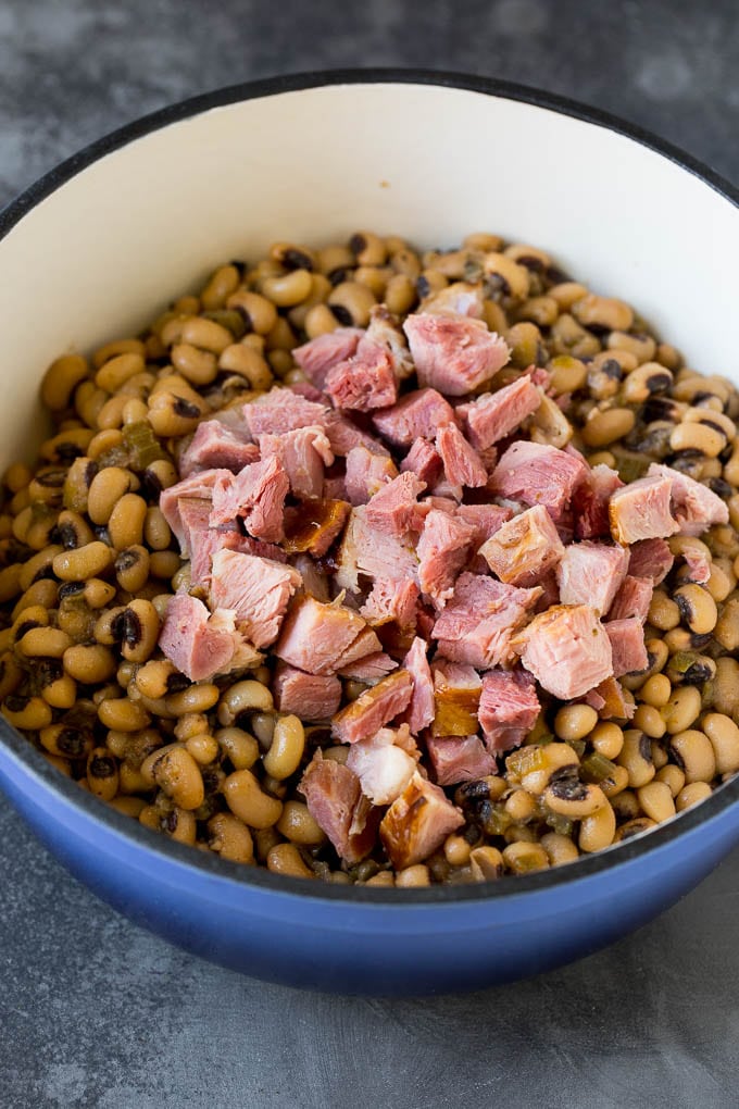 This Hoppin' John recipe is black eyed peas simmered with ham and vegetables until tender, then served over rice. Diced ham in a pot of cooked black eyed peas.