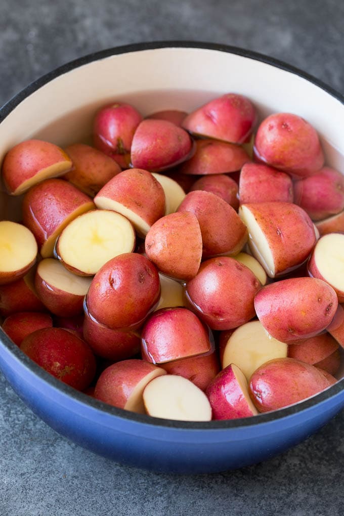 These mashed red potatoes are tender potatoes combined with garlic, butter and seasonings to make a simple yet totally satisfying side dish. Halved red potatoes in a pot of water.