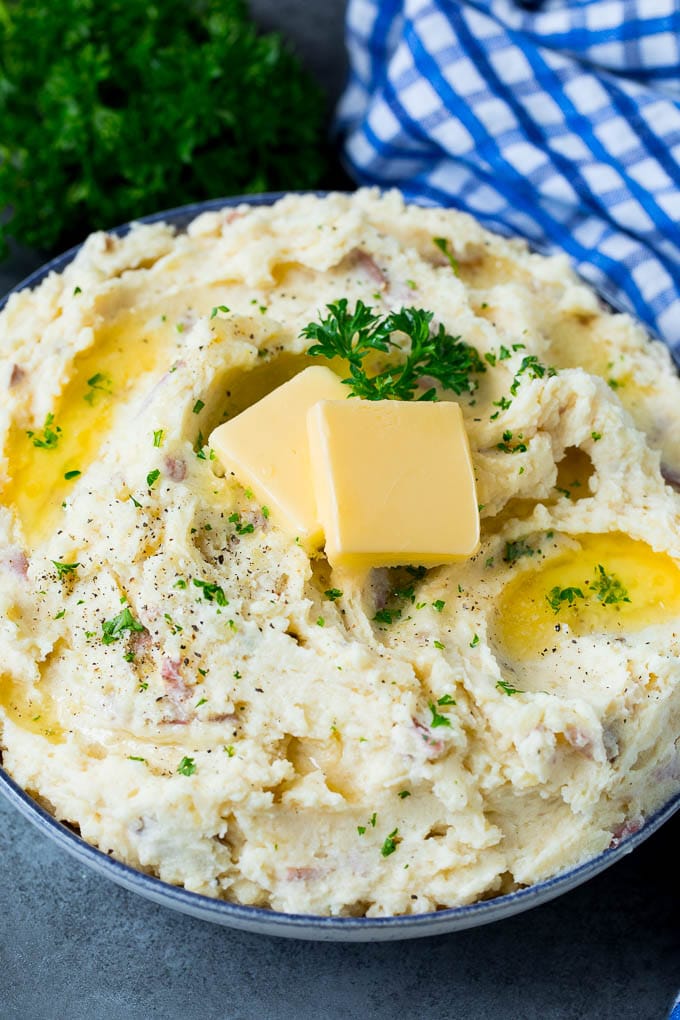 These mashed red potatoes are tender potatoes combined with garlic, butter and seasonings to make a simple yet totally satisfying side dish. A bowl of red mashed potatoes with butter and chopped herbs.