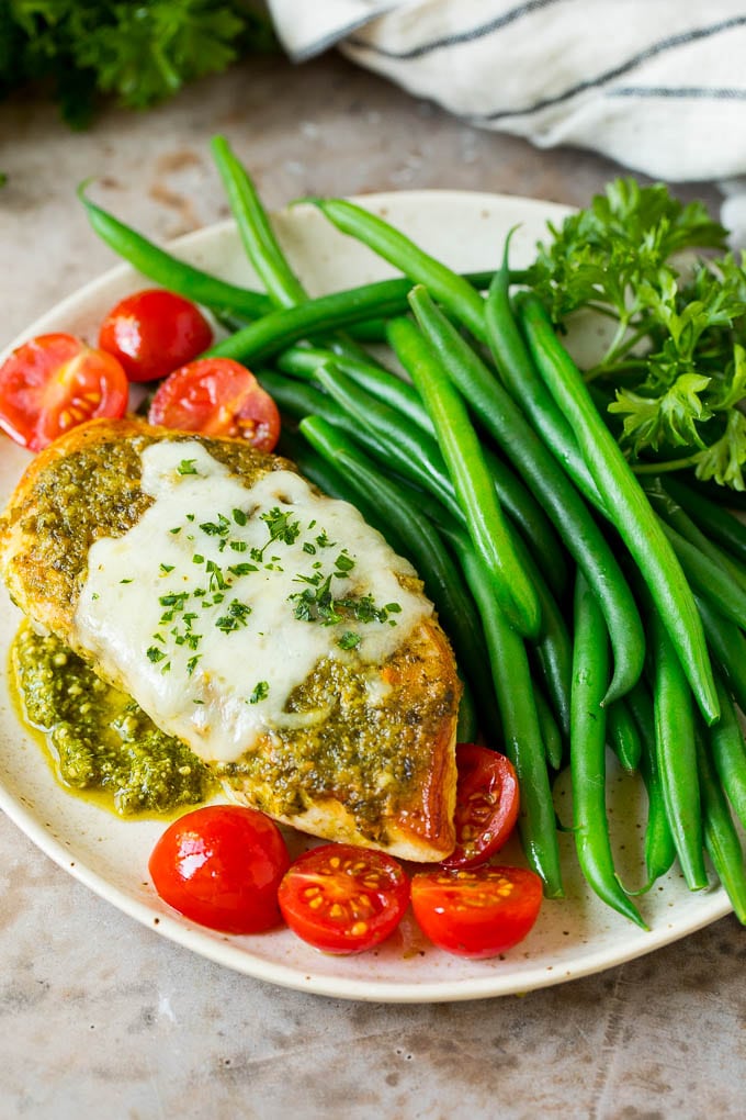 A plate of pesto chicken served with green beans.