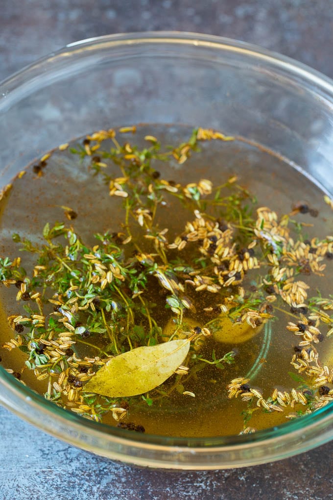 This pork chop brine is a blend of salt, sugar, herbs and spices that infuses the meat with flavor and helps to keep it tender and juicy. A bowl of pork chop brine made with fennel seeds, thyme, pepper and garlic.