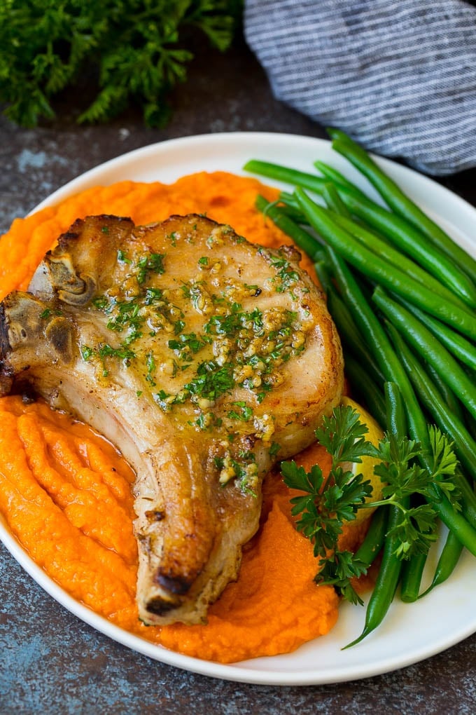 This pork chop brine is a blend of salt, sugar, herbs and spices that infuses the meat with flavor and helps to keep it tender and juicy. Meat served with sweet potatoes and green beans.