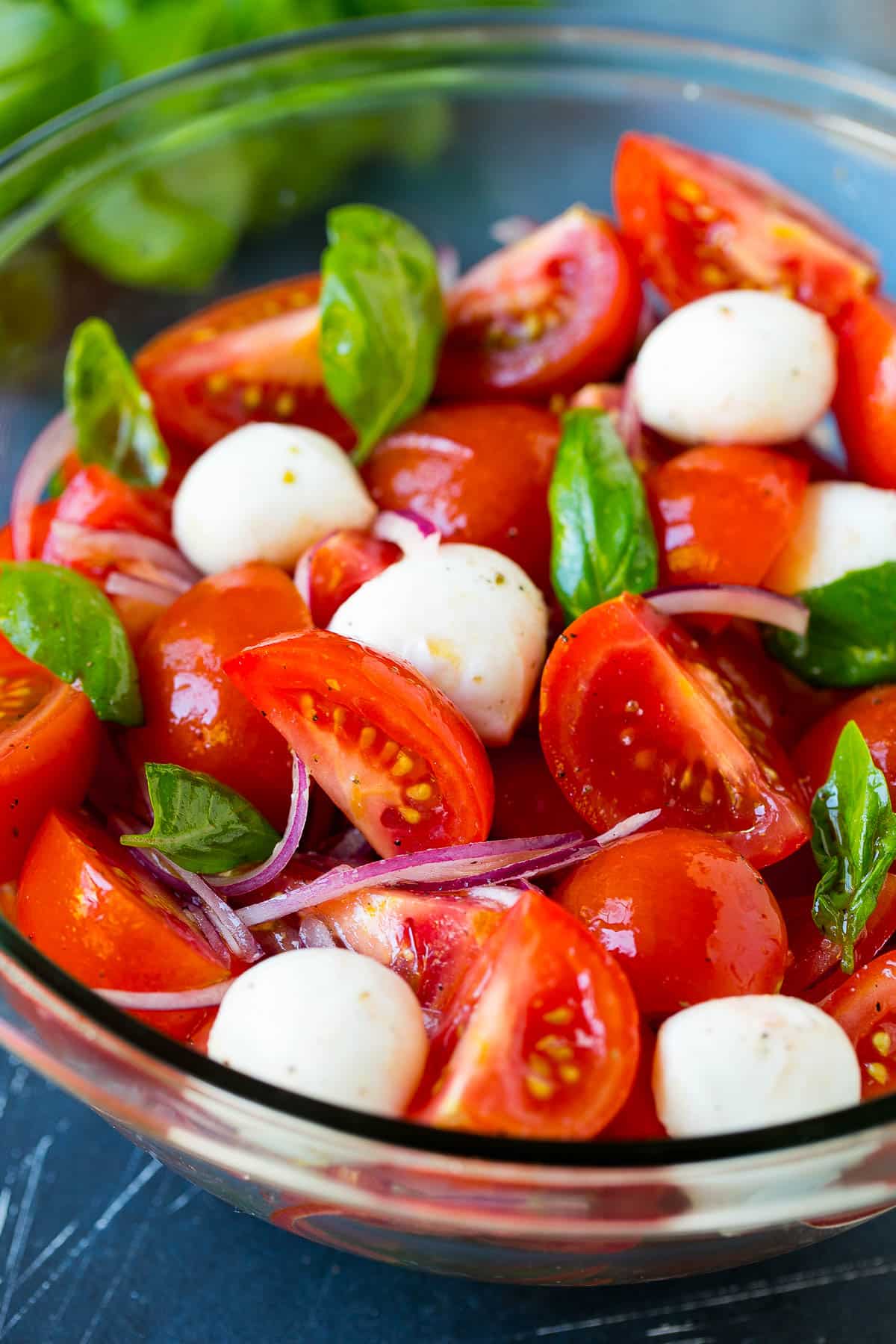 A close up of the dressed herbs, veggies and cheese in a bowl.