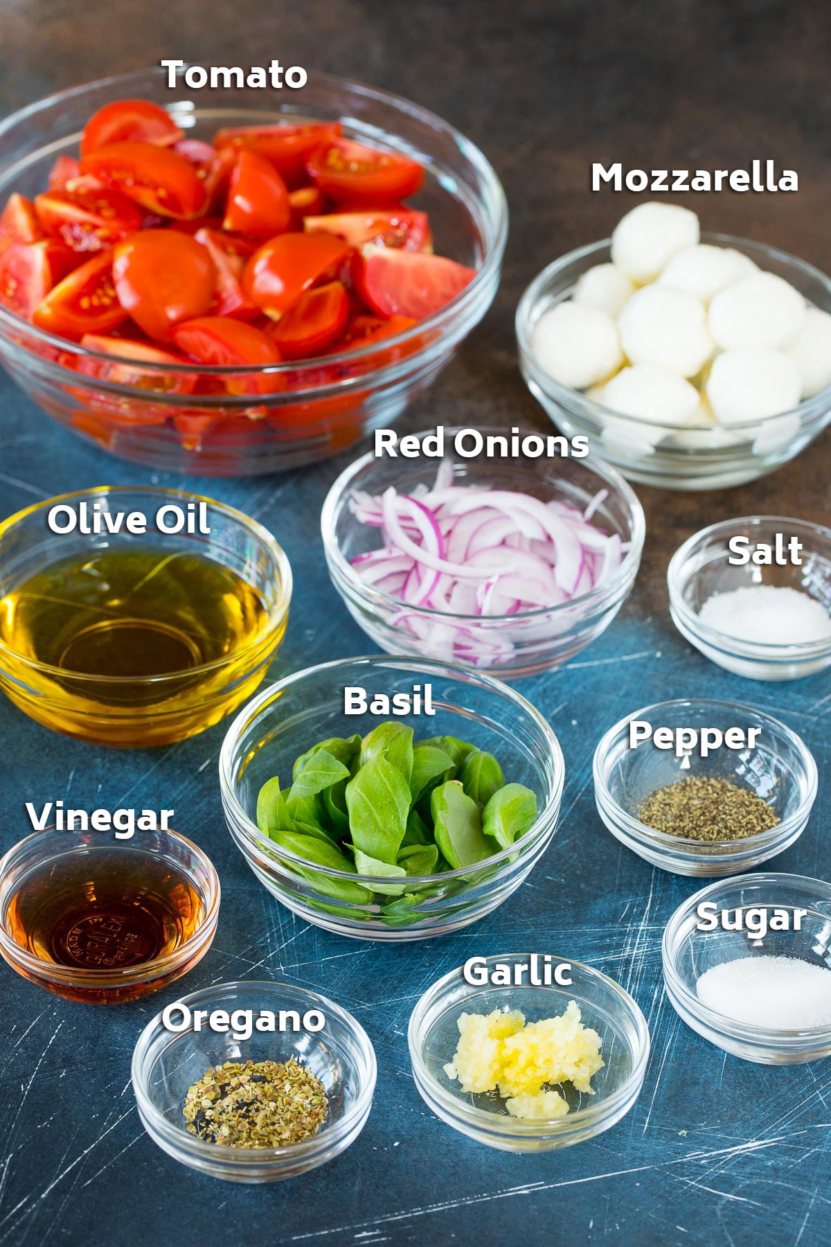 Bowls of ingredients including basil, cheese, onions, olive oil and seasonings.