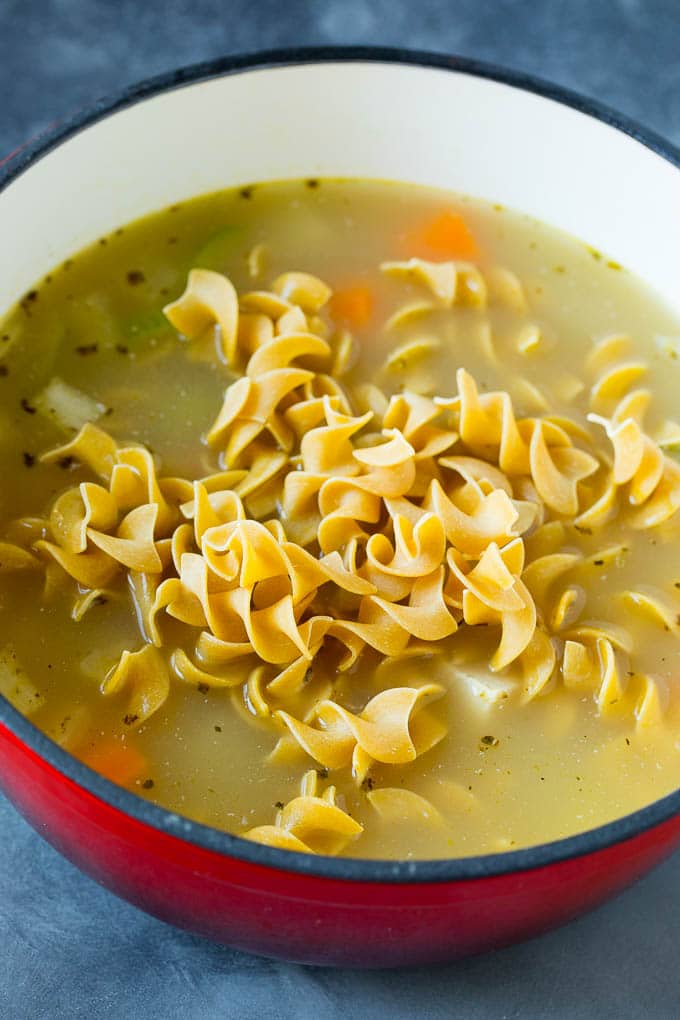 This turkey soup recipe is homemade turkey broth loaded with vegetables, diced turkey and egg noodles. A pot of soup with egg noodles on top.