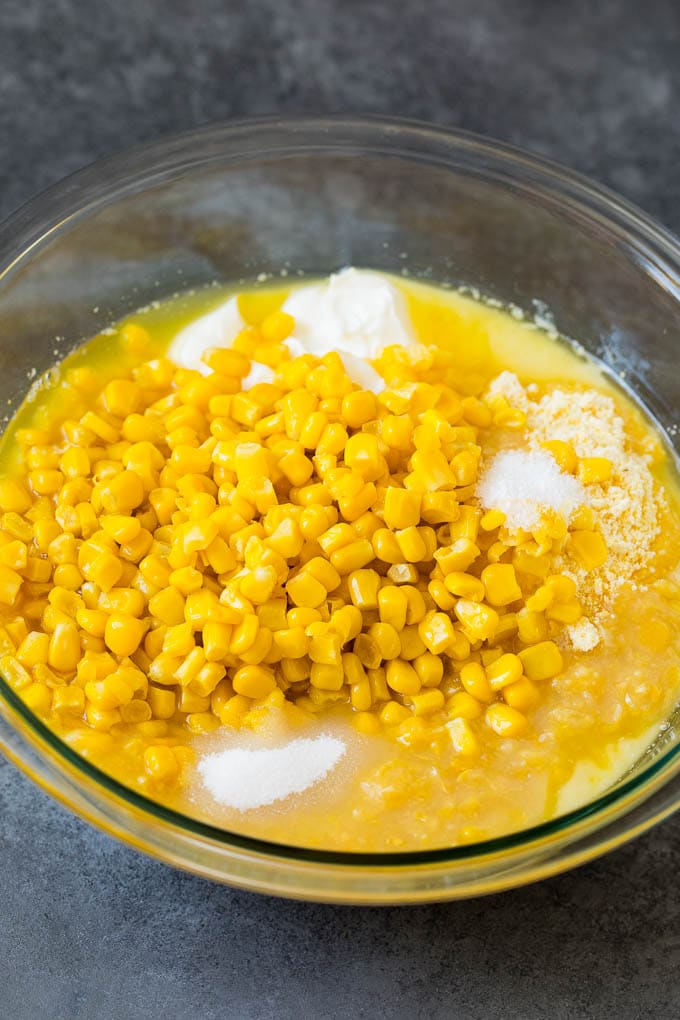 This corn souffle recipe is a flavorful blend of corn kernels, butter, eggs and creamed corn, all baked to light and fluffy perfection. Corn muffin mix, corn kernels, sour cream and seasonings in a bowl.