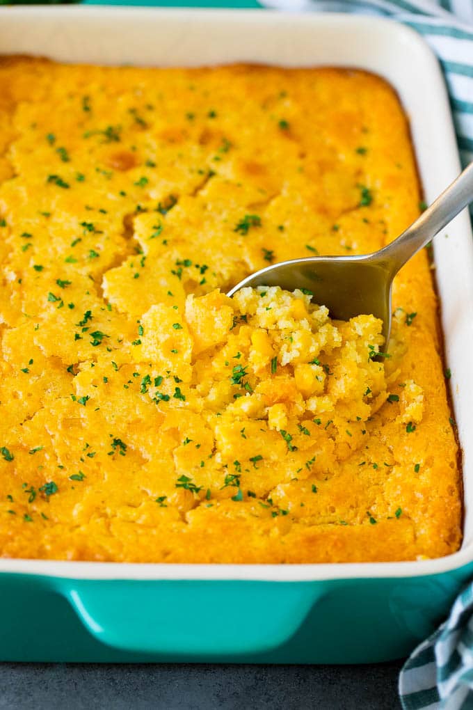 This corn souffle recipe is a flavorful blend of corn kernels, butter, eggs and creamed corn, all baked to light and fluffy perfection. A dish of corn souffle with a serving spoon in it.