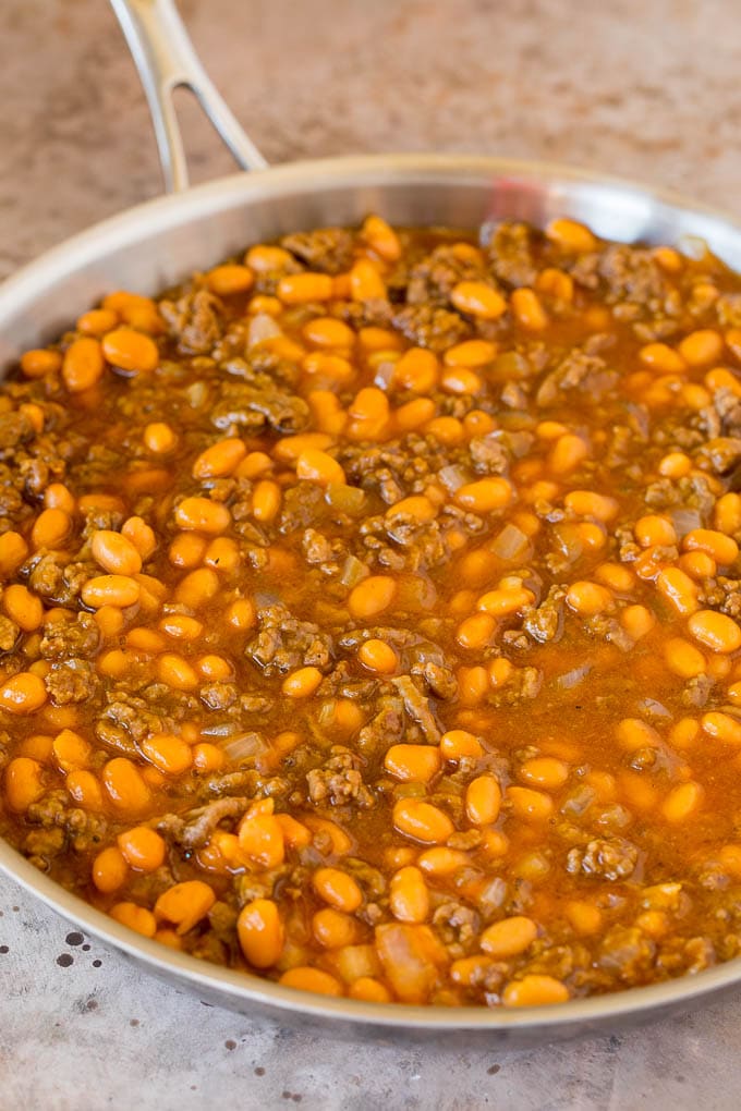 This cowboy beans recipe is made with ground beef and bacon, all baked together in a sweet and savory sauce. Beans, ground beef and seasonings in a pan.