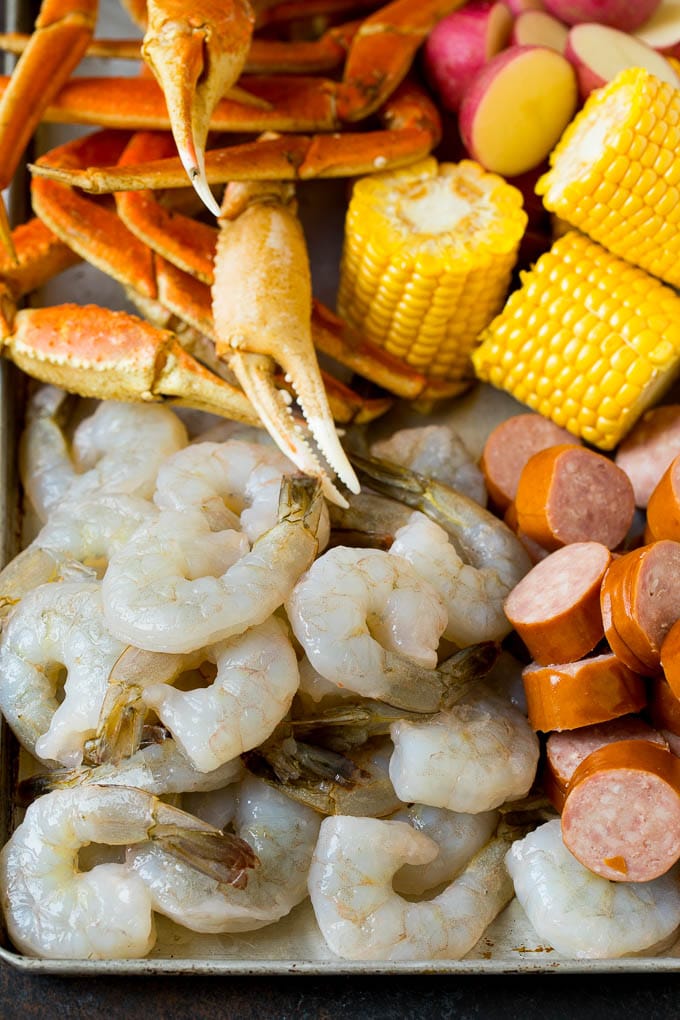 This Low Country Boil is a blend of shrimp, crab, sausage, corn and potatoes, all cooked together to create a hearty dinner. Shrimp, sliced sausage, crab legs and corn cobs on a sheet pan.