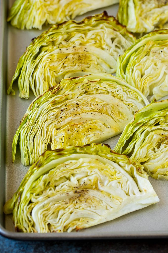 This roasted cabbage recipe is wedges of cabbage seasoned with olive oil and spices, then oven baked until tender and browned. Cooked cabbage wedges laying on a sheet pan.
