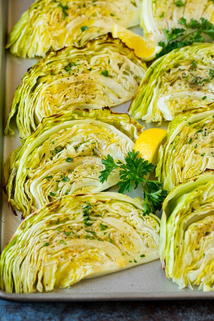 This roasted cabbage recipe is wedges of cabbage seasoned with olive oil and spices, then oven baked until tender and browned. Roasted cabbage on a pan topped with fresh parsley.