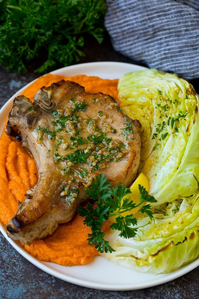 This roasted cabbage recipe is wedges of cabbage seasoned with olive oil and spices, then oven baked until tender and browned. Roasted cabbage served with pork chops and sweet potatoes.