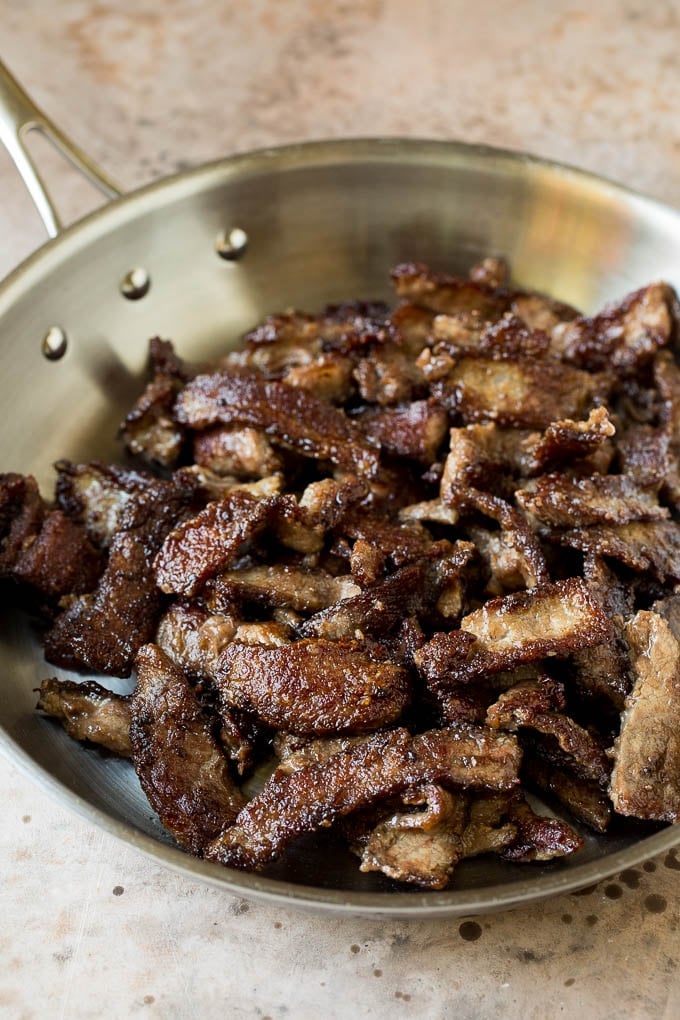 This Szechuan beef is a spicy stir fry made with tender pieces of beef and colorful vegetables, all tossed in a sweet and savory sauce. Seared beef slices in a pan.