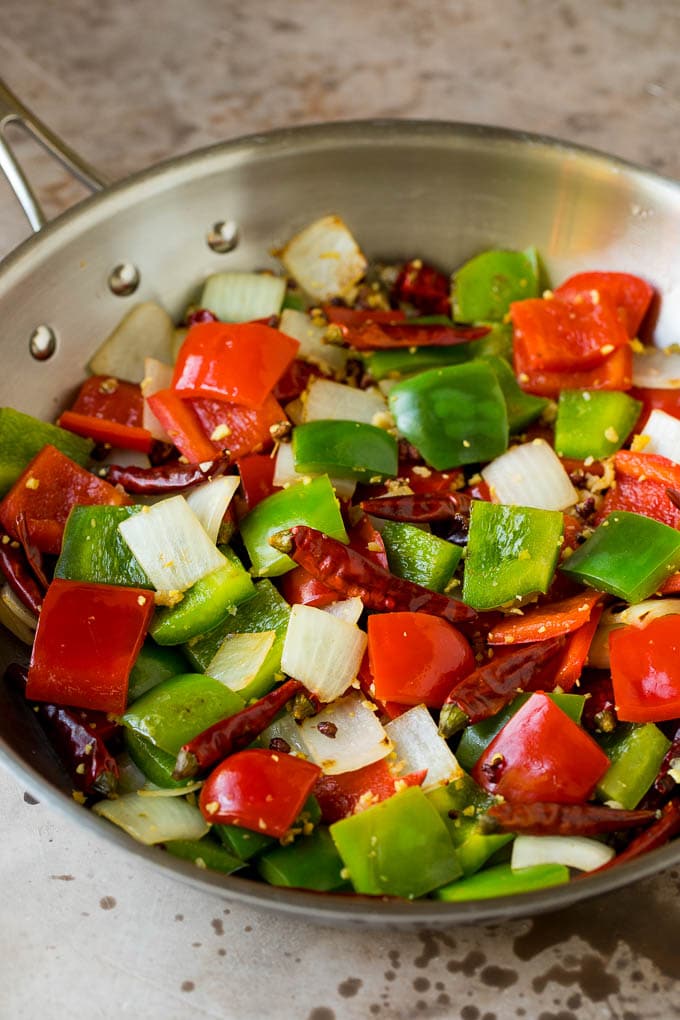 This Szechuan beef is a spicy stir fry made with tender pieces of beef and colorful vegetables, all tossed in a sweet and savory sauce. Sauteed vegetables, chilis and peppercorns in a skillet.