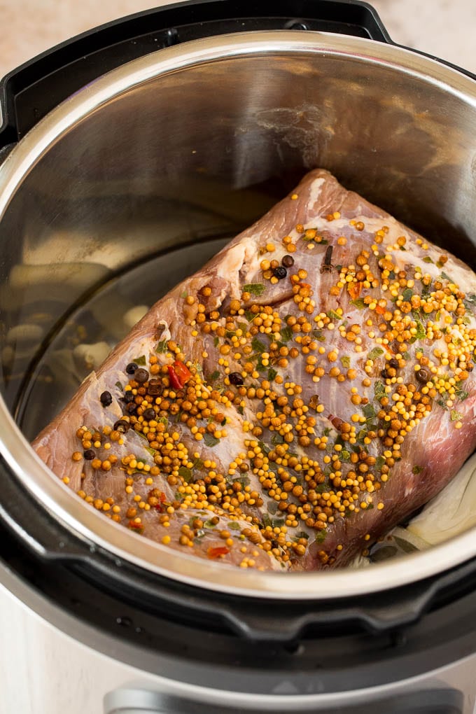 This Instant Pot corned beef is pressure cooked until tender, then served with potatoes, cabbage and carrots in a garlic butter sauce. An easy one pot meal that's great for St. Patrick's Day or any other day of the year! A raw corned beef in a pressure cooker.