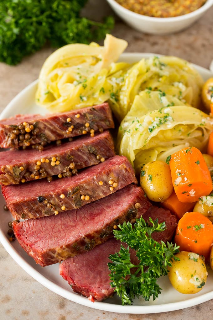 This Instant Pot corned beef is pressure cooked until tender, then served with potatoes, cabbage and carrots in a garlic butter sauce. An easy one pot meal that's great for St. Patrick's Day or any other day of the year! A plate of sliced Instant Pot corned beef with cabbage wedges, carrots and baby potatoes.