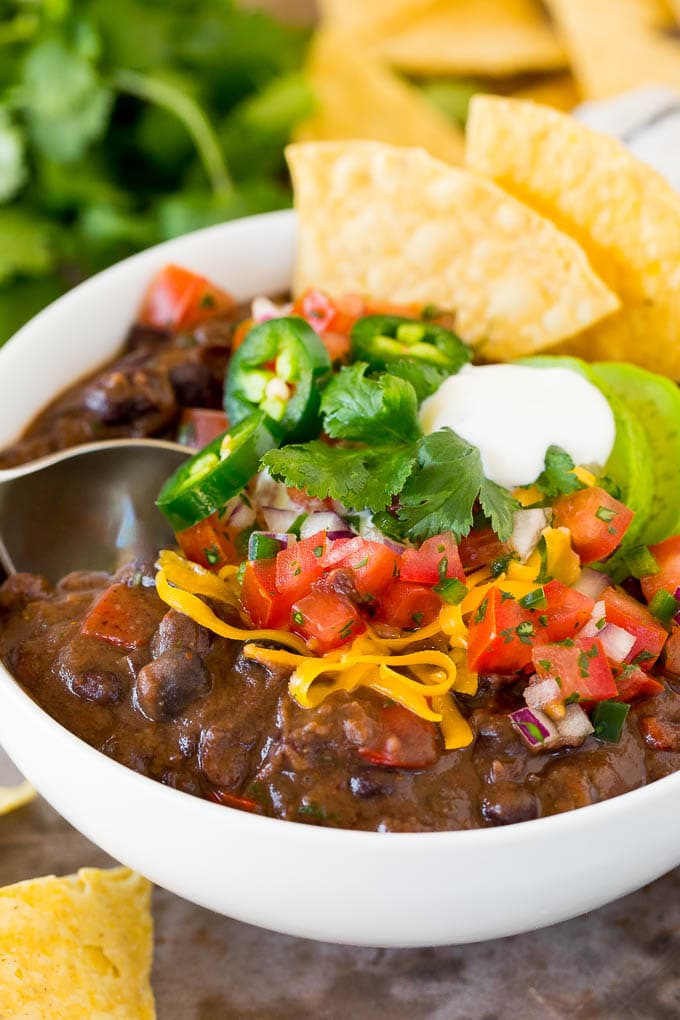 This black bean soup is a zesty blend of beans and vegetables, simmered together to make a thick and hearty meal. Add your favorite toppings and you'll have an easy and healthy dinner option that's sure to get rave reviews! A spoon in a bowl of black bean soup.