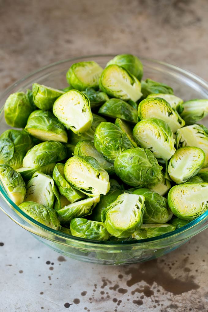 These crispy Brussels sprouts are coated in olive oil, garlic and seasonings, then roasted at high heat until tender and golden brown. Halved sprouts in a bowl.