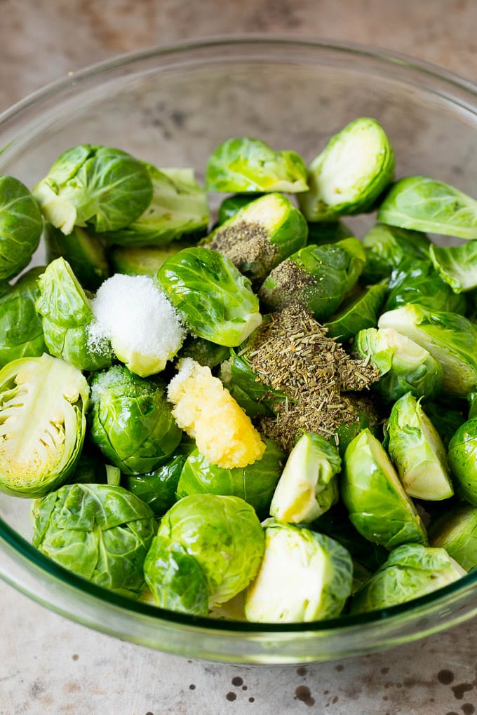 These crispy Brussels sprouts are coated in olive oil, garlic and seasonings, then roasted at high heat until tender and golden brown. A bowl of Brussels sprouts with garlic, herbs, olive oil and spices.