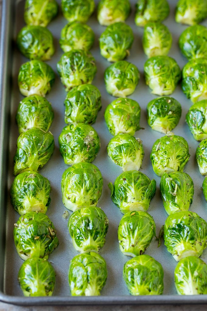 These crispy Brussels sprouts are coated in olive oil, garlic and seasonings, then roasted at high heat until tender and golden brown. Brussels sprouts lined up face down on a sheet pan.