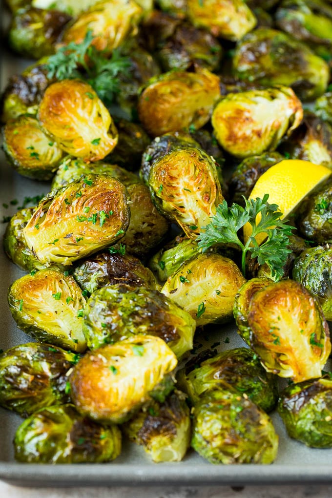 These crispy Brussels sprouts are coated in olive oil, garlic and seasonings, then roasted at high heat until tender and golden brown. Crispy Brussels sprouts garnished with lemon slices and parsley.