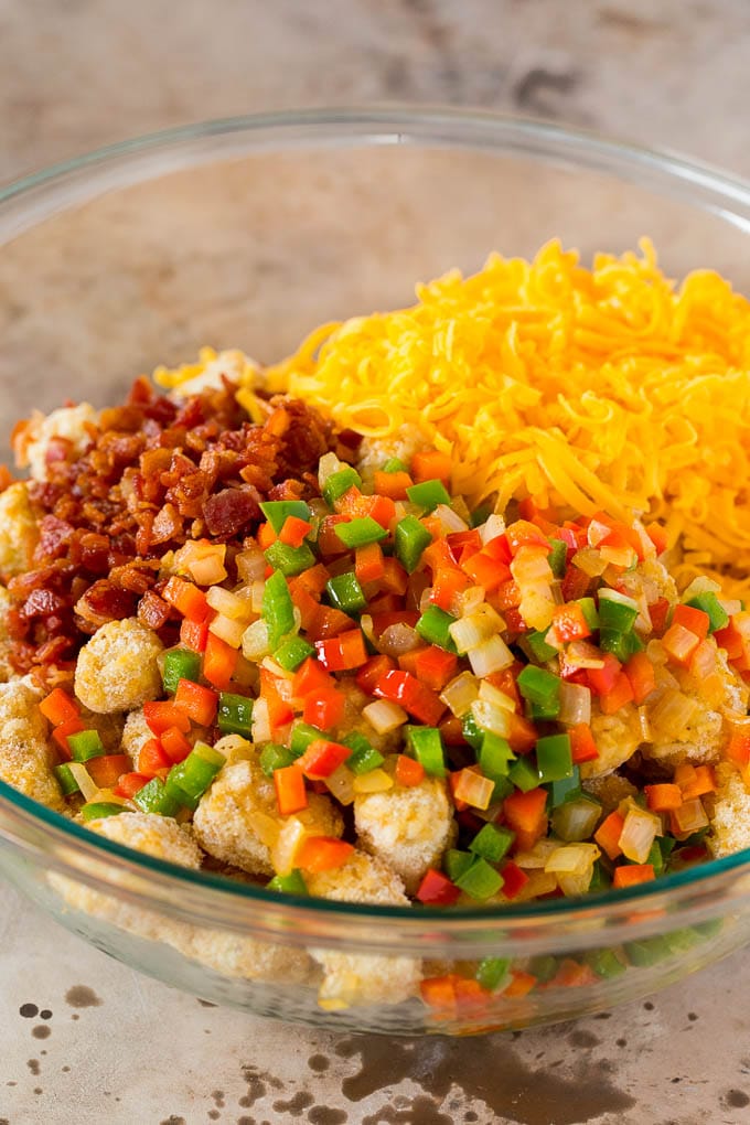 This tater tot breakfast casserole is made with bacon, eggs, veggies, potato tots and plenty of cheese, all baked together to make a hearty meal. A bowl of frozen tater tots, vegetables, bacon and shredded cheese.