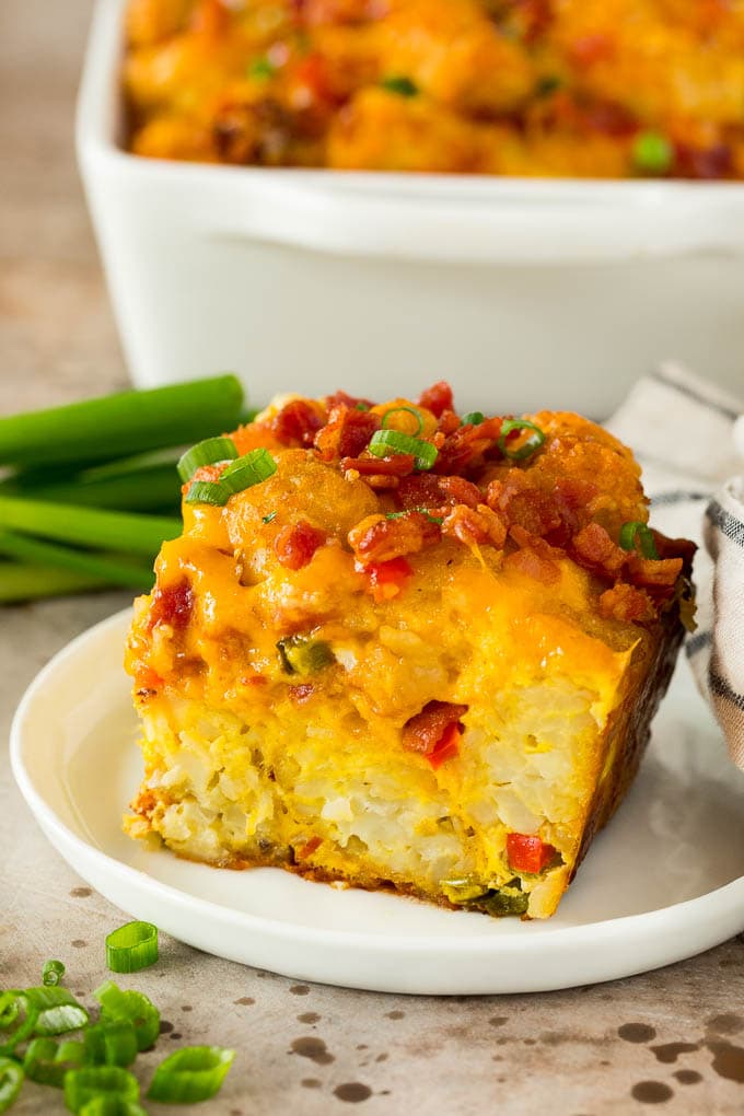 This tater tot breakfast casserole is made with bacon, eggs, veggies, potato tots and plenty of cheese, all baked together to make a hearty meal. A slice of tater tot breakfast casserole on a plate.