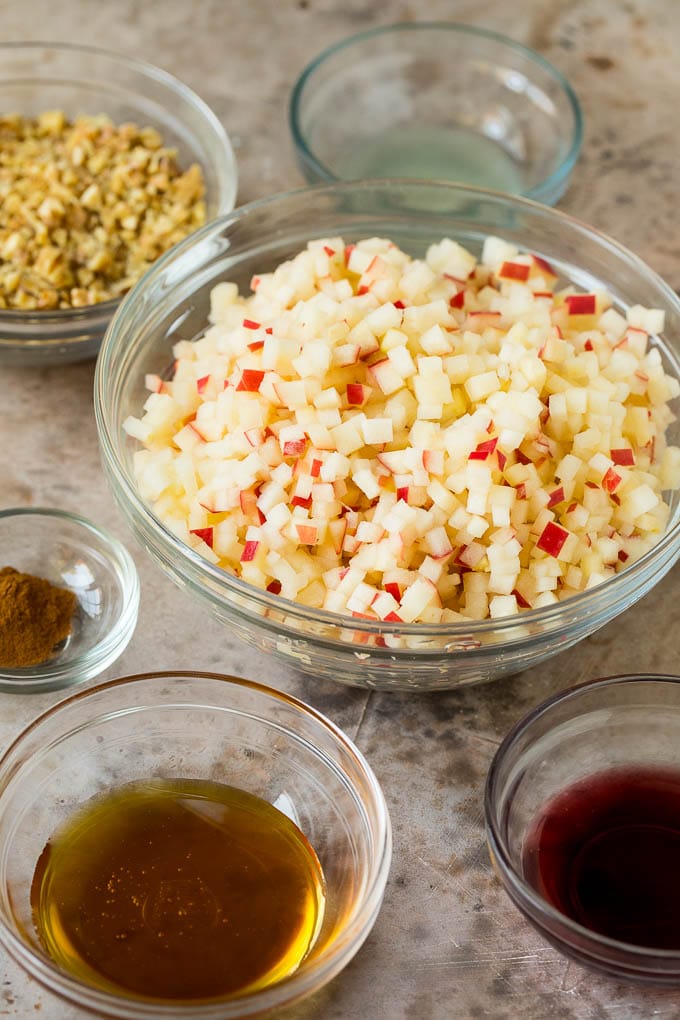 This charoset recipe is a blend of apples, walnuts and honey, all mixed together to make a sweet spread that's an essential part of any Passover meal. Bowls of chopped apples, honey, wine and cinnamon.