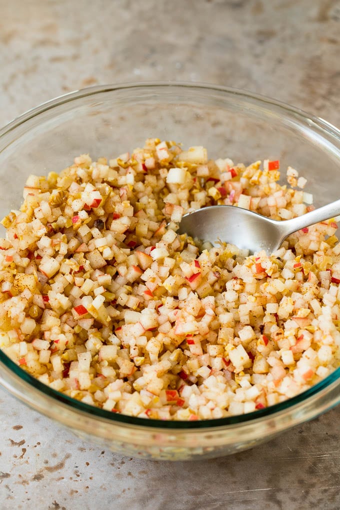 This charoset recipe is a blend of apples, walnuts and honey, all mixed together to make a sweet spread that's an essential part of any Passover meal. A mixing bowl filled with diced apples, cinnamon and sweetener.