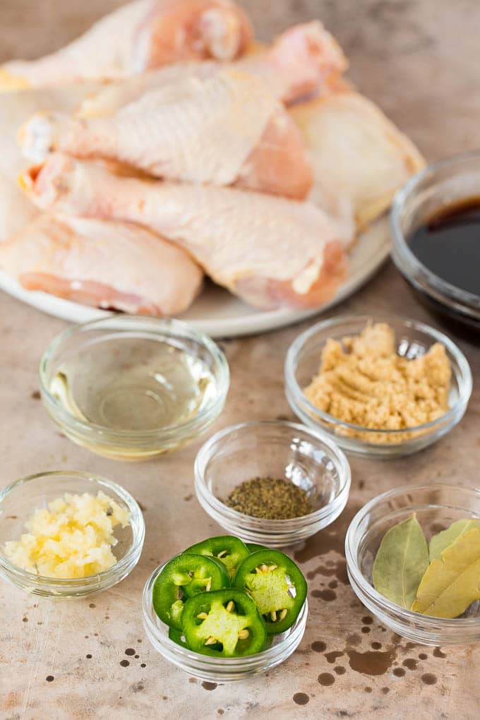 This chicken adobo is a Filipino dish made with chicken pieces simmered in a sweet and savory sauce. An easy dinner option with minimal ingredients that always gets rave reviews! Small bowls of ingredients including jalapenos, brown sugar, garlic and bay leaves.