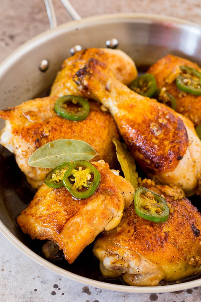 This chicken adobo is a Filipino dish made with chicken pieces simmered in a sweet and savory sauce. An easy dinner option with minimal ingredients that always gets rave reviews! A pan of chicken with jalapenos, soy sauce and garlic.