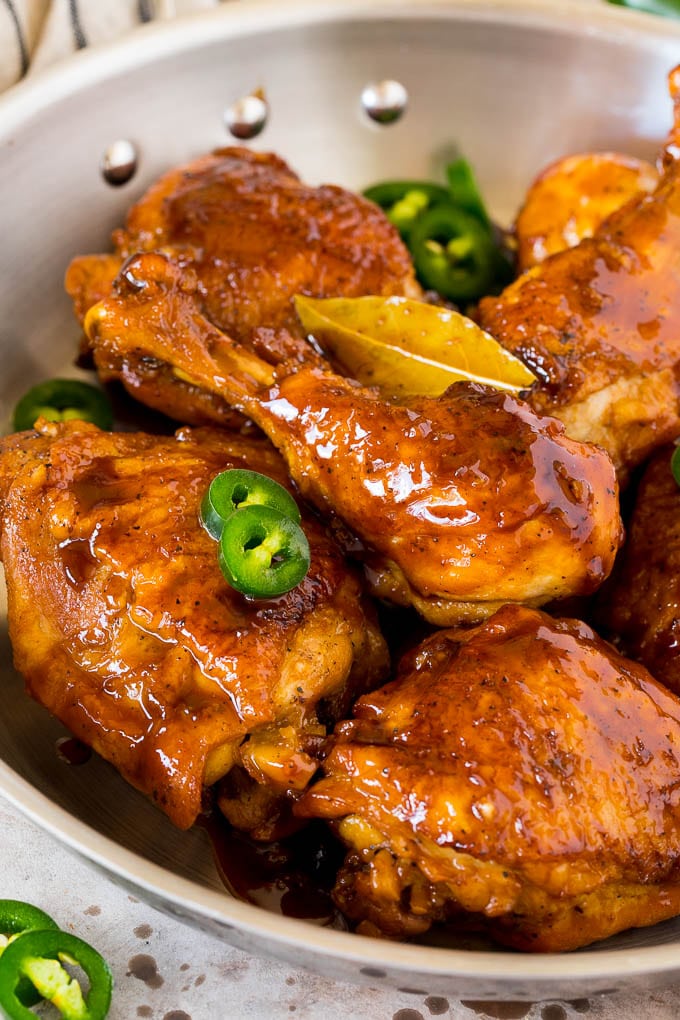 This chicken adobo is a Filipino dish made with chicken pieces simmered in a sweet and savory sauce. An easy dinner option with minimal ingredients that always gets rave reviews! A pan of chicken adobo garnished with sliced jalapeno.