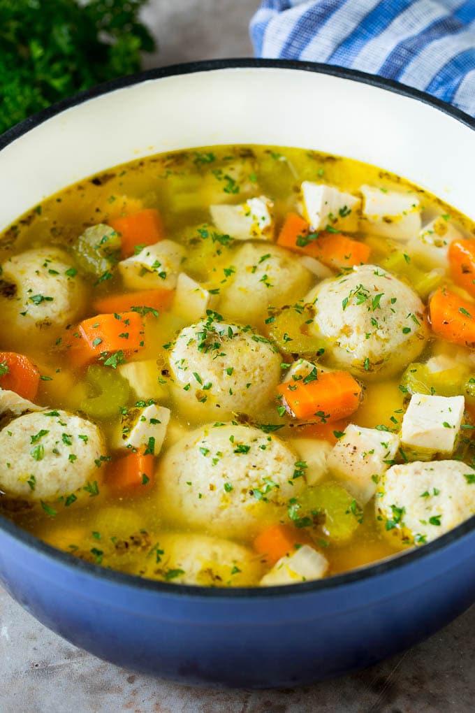 This matzo ball soup is chicken and vegetables simmered with matzo balls in a savory broth with fresh herbs. A pot of matzo ball soup with chicken and vegetables.