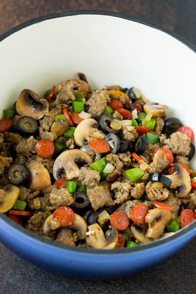This pizza casserole is pasta simmered in tomato sauce with pepperoni, sausage, olives and bell peppers. Sausage, mushrooms, olives, pepperoni and peppers in a pot.