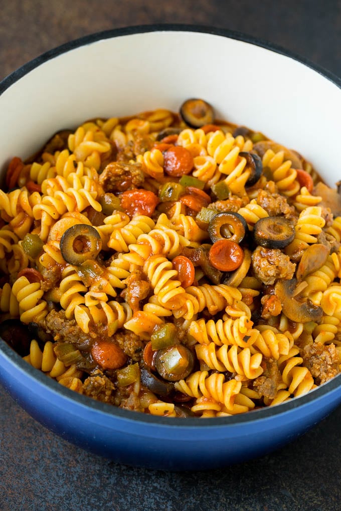 This pizza casserole is pasta simmered in tomato sauce with pepperoni, sausage, olives and bell peppers. Cooked pasta with meat and vegetables in a pot.