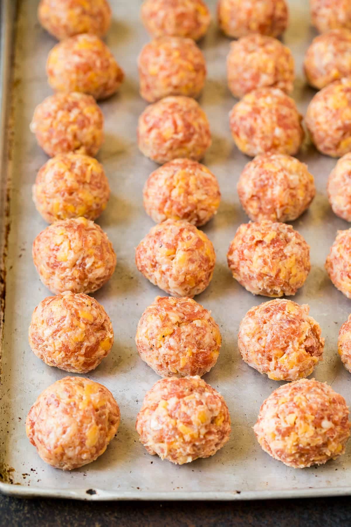 Raw sausage balls on a sheet pan.
