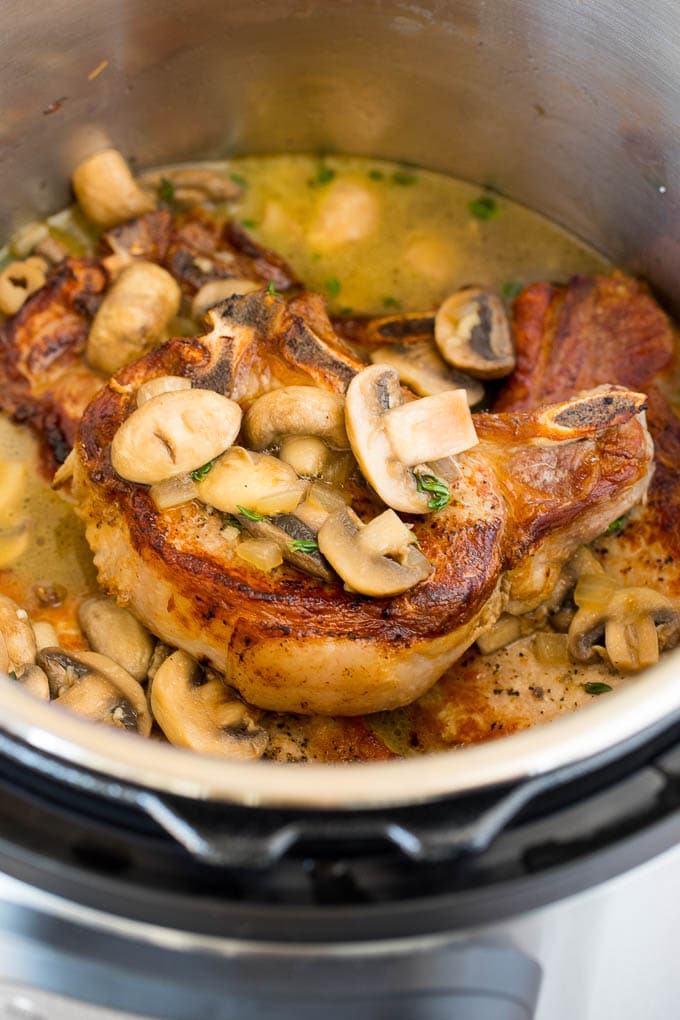 A pot of pork chops topped with mushrooms.