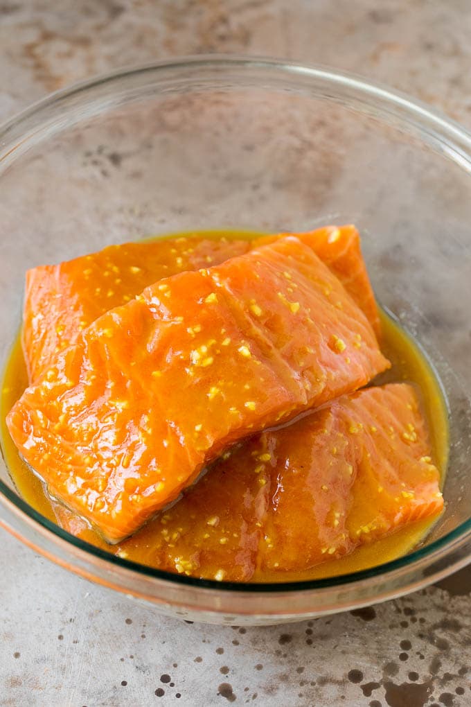This miso salmon is fresh fish fillets soaked in a flavorful marinade, then broiled to perfection and topped with sesame seeds. Salmon in a bowl of marinade.