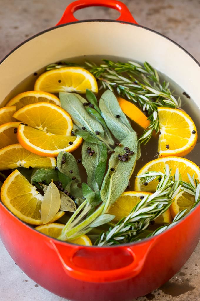 This is a complete guide on how to brine a turkey to get the most tender and flavorful bird each and every time. A pot of liquid with oranges, herbs and peppercorns.