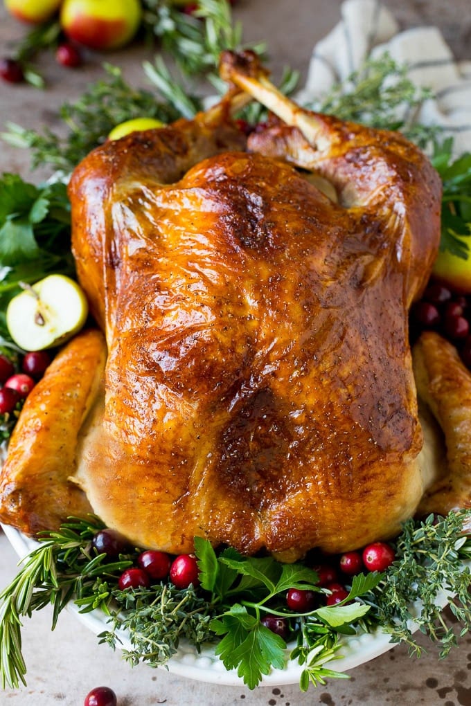 This is a complete guide on how to brine a turkey to get the most tender and flavorful bird each and every time. Learn how to brine a turkey to make this cooked turkey garnished with herbs.