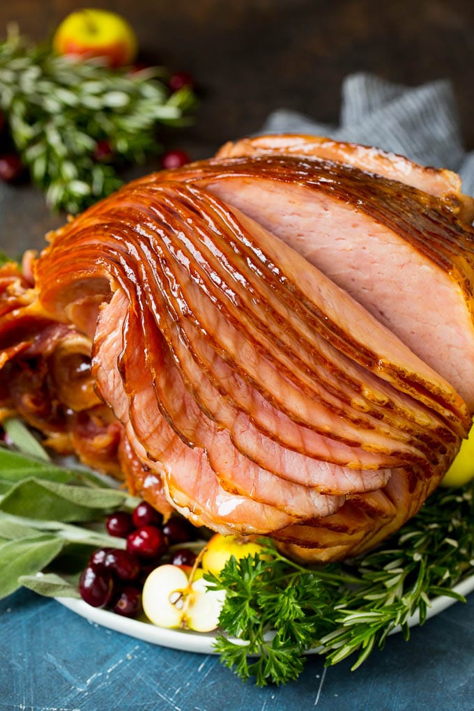 This Instant Pot ham is a spiral ham coated in a 3 ingredient glaze, then pressure cooked to tender perfection. An Instant Pot ham served on a platter with herbs and fruit.