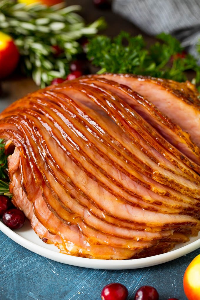This Instant Pot ham is a spiral ham coated in a 3 ingredient glaze, then pressure cooked to tender perfection. Sliced ham on a plate garnished with cranberries.