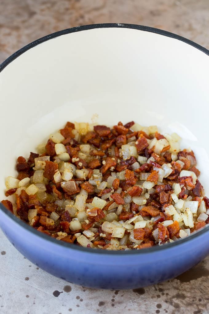 These Southern style mustard greens are cooked with smoky bacon and seasonings until tender and flavorful. Cooked bacon and onions in a pot.