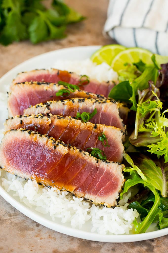 This seared ahi tuna recipe is sashimi grade fish coated in sesame seeds, then briefly cooked to tender and flavorful perfection. Seared ahi tuna served with rice and salad.