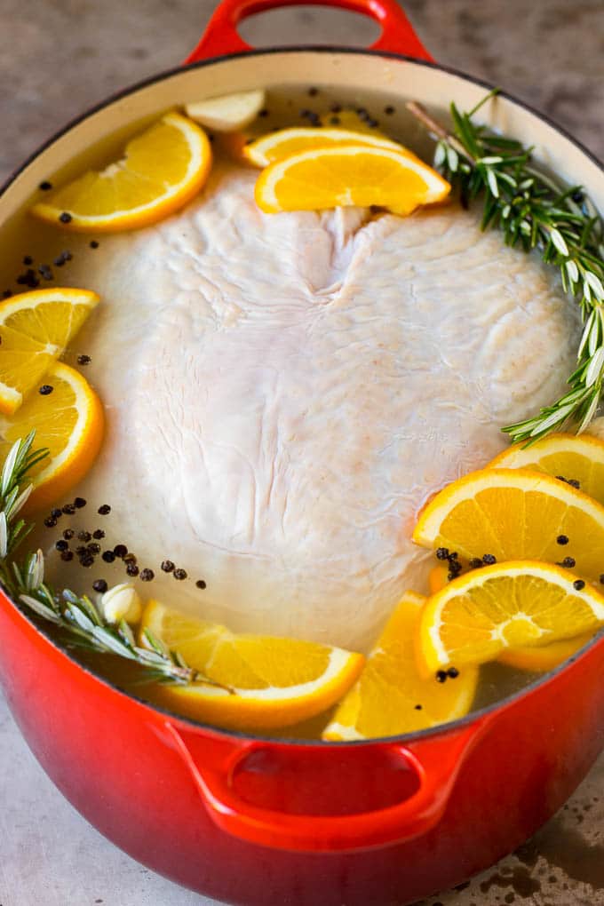 This smoked turkey breast is soaked in brine, then coated in homemade spice rub and cooked on a smoker until it is tender and juicy. A raw breast in a pot of brine.