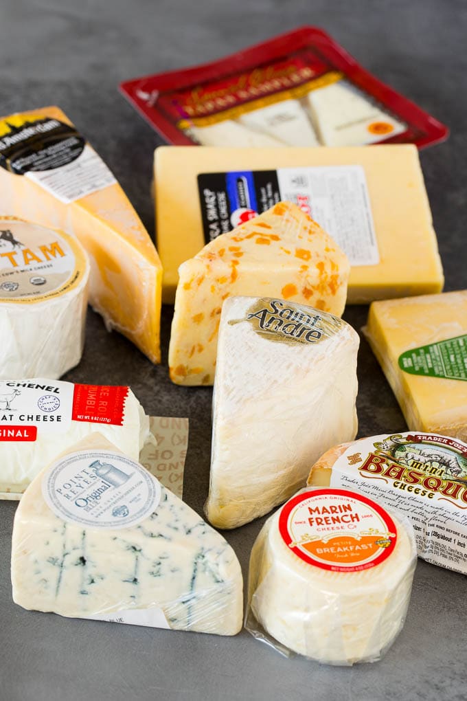A guide to creating the best cheese board with a variety of different cheeses, crackers, fruit and accompaniments. Different cheeses wrapped in plastic.